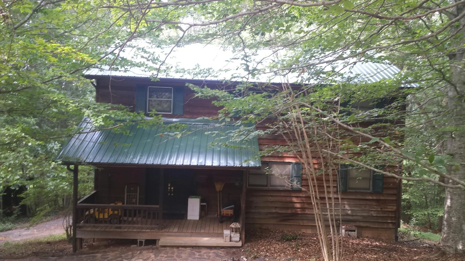 Green metal roof and covered porch on a log cabin in Edgar