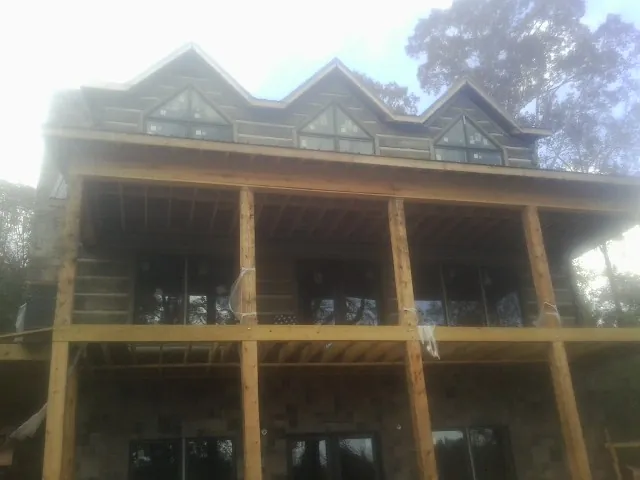 Dormers and porch framing on a large log home under construction — Roof Coating work by our crew in Edgar