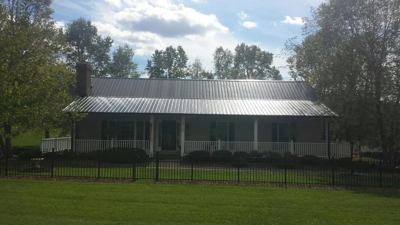 Gray metal roof on a brick ranch with a full width front porch — Gutter Guard Installation work by our crew in Edgar