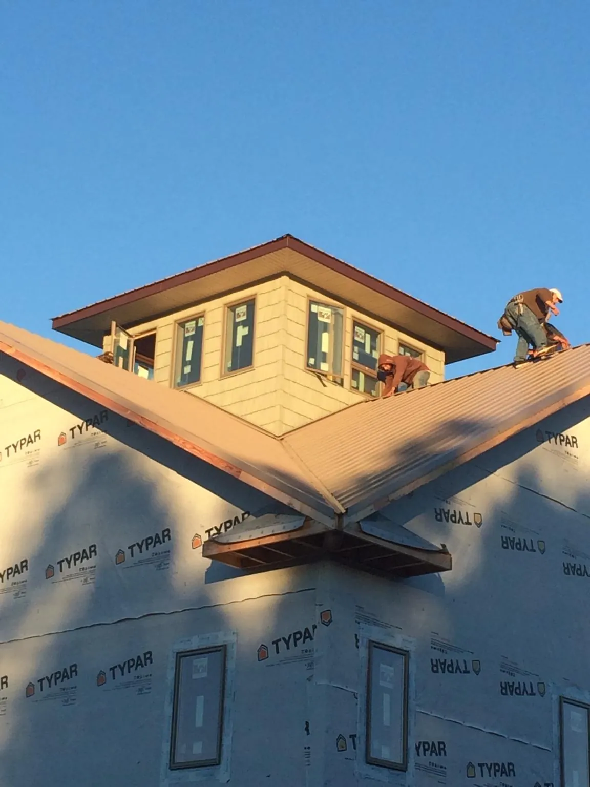 Roofers working around a rooftop cupola on a new metal roof at sunset — Roof Waterproofing in Edgar by Roofing Brothers